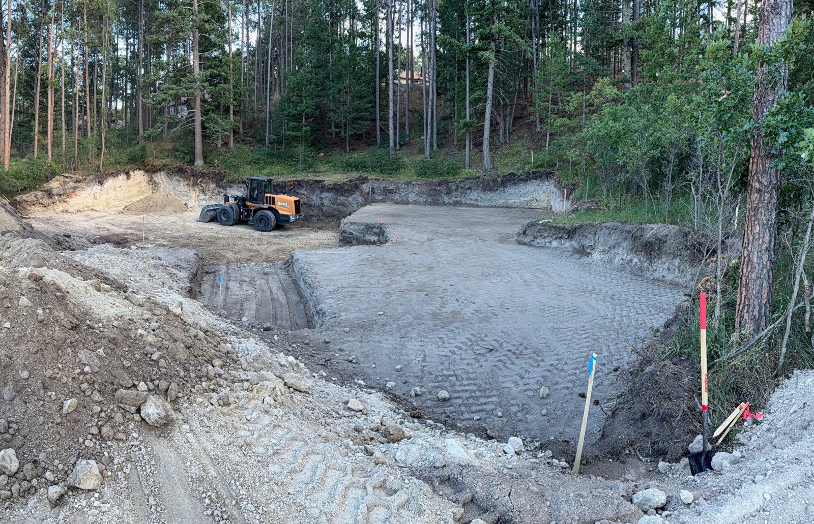 Excavator and dozer cutting a building pad on a dirt work site