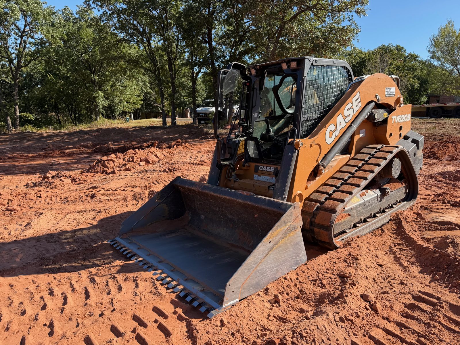 Case track loader with a toothed bucket on a red dirt job site